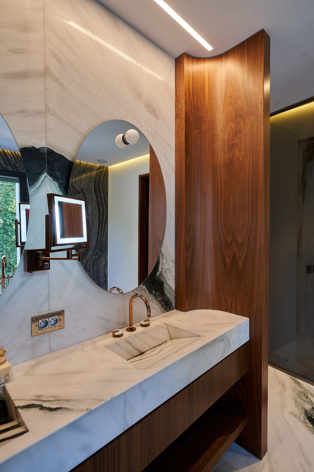 Habillage mural cintré en placage noyer naturel dans une salle de bain en marbre, AMARGUS Contract