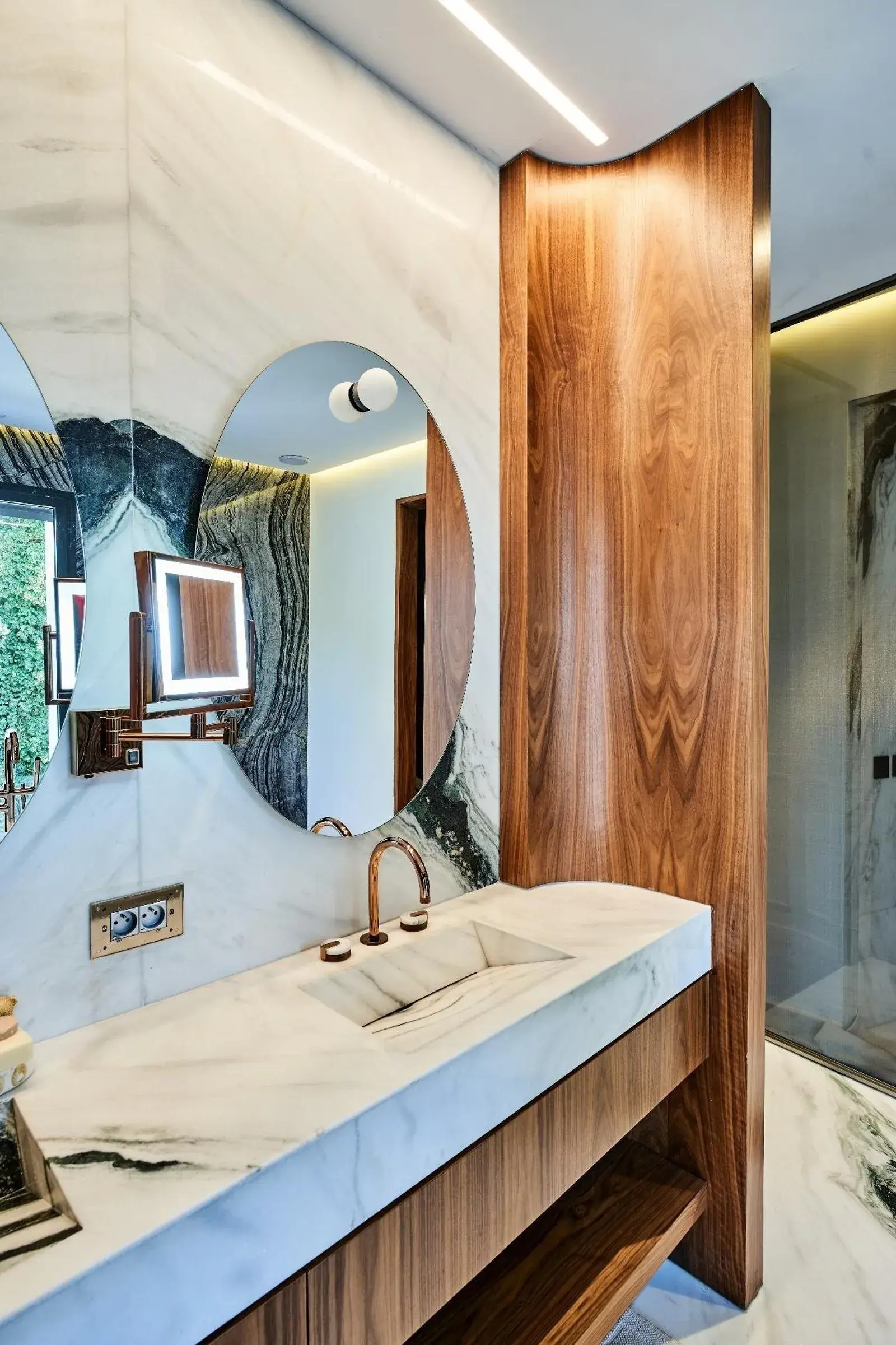 Salle de bain master : vasque en marbre blanc, panneau de noyer cintré et miroir rétroéclairé