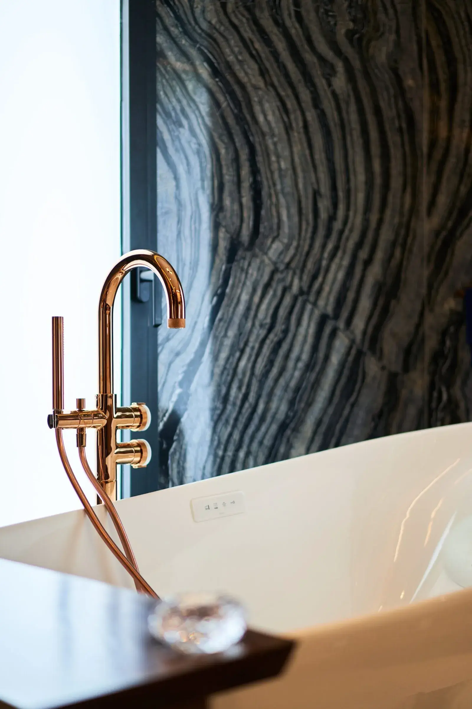 Robinetterie GRAFF cuivre rosé et baignoire TOTO Flotation Tub devant le marbre Silver Wave