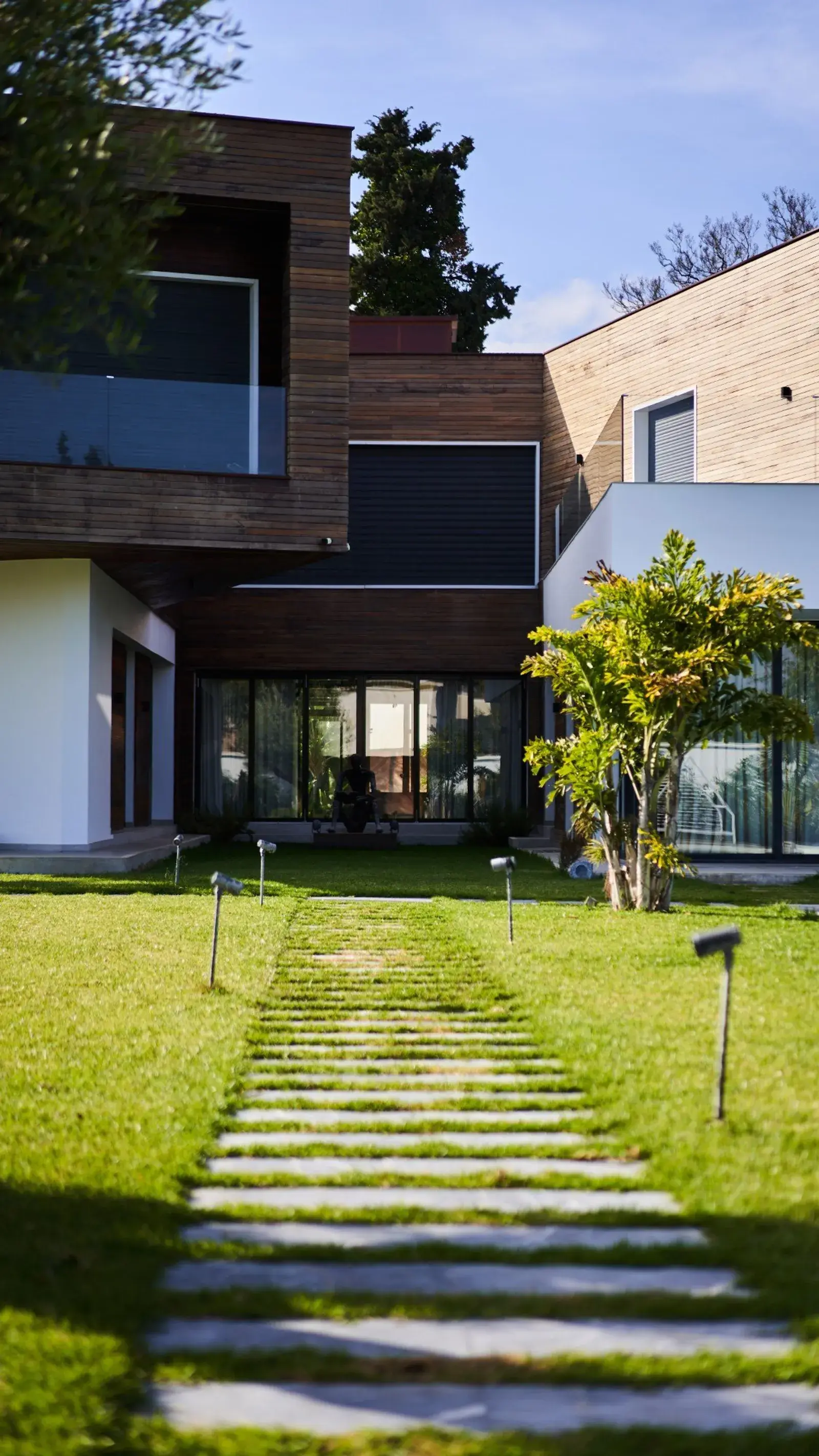 Façade en bardage bois et allée de pas japonais dans le jardin